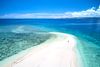 An aerial view of a small piece of land with white-sand in the middle of turquoise waters.
