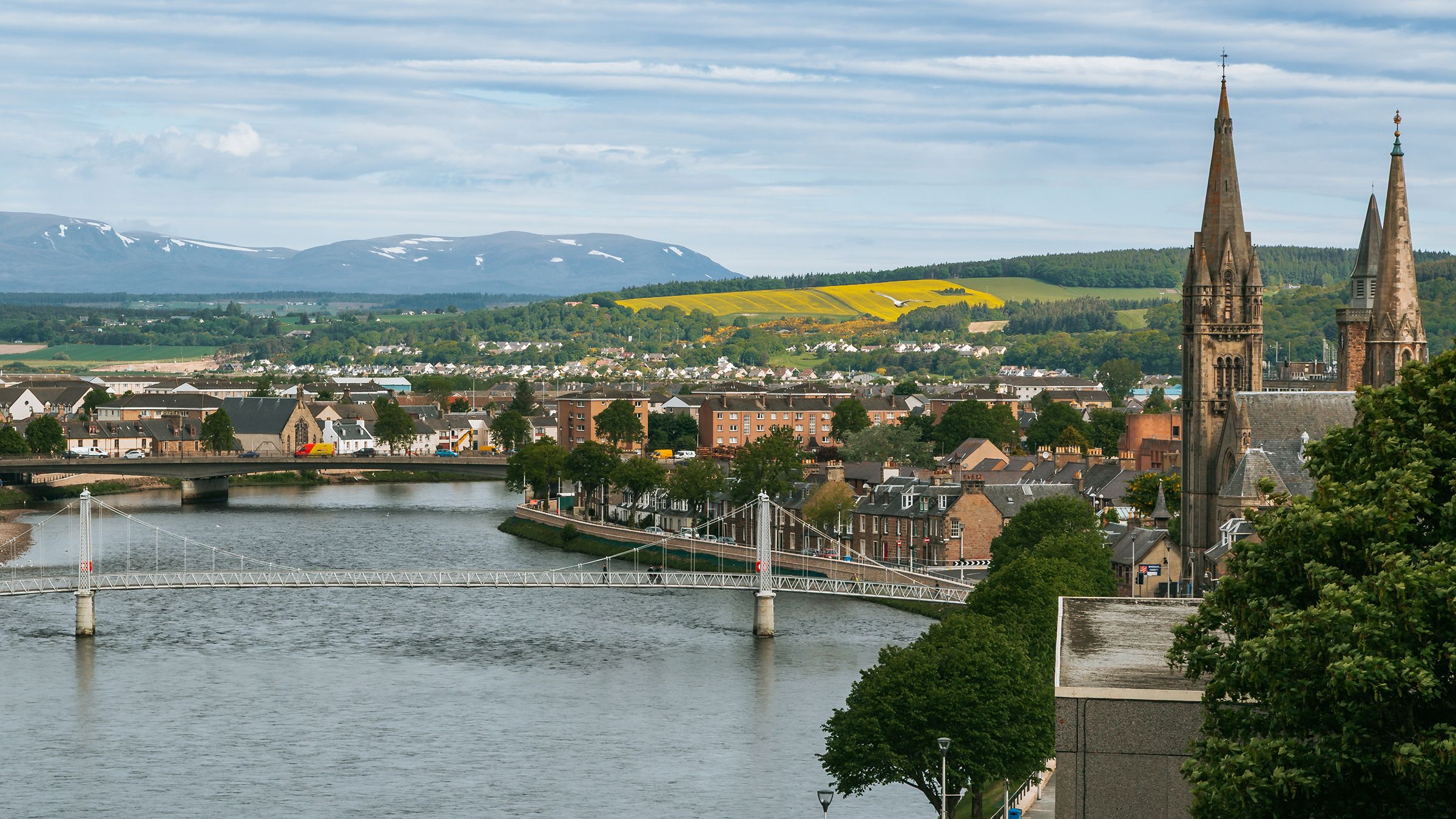 Inverness riverside view showcasing historic architecture and scenic landscapes with distant mountains in Scotland