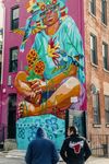 A large, colorful mural adorns the side of a multi-storey building in Pilsen, Chicago