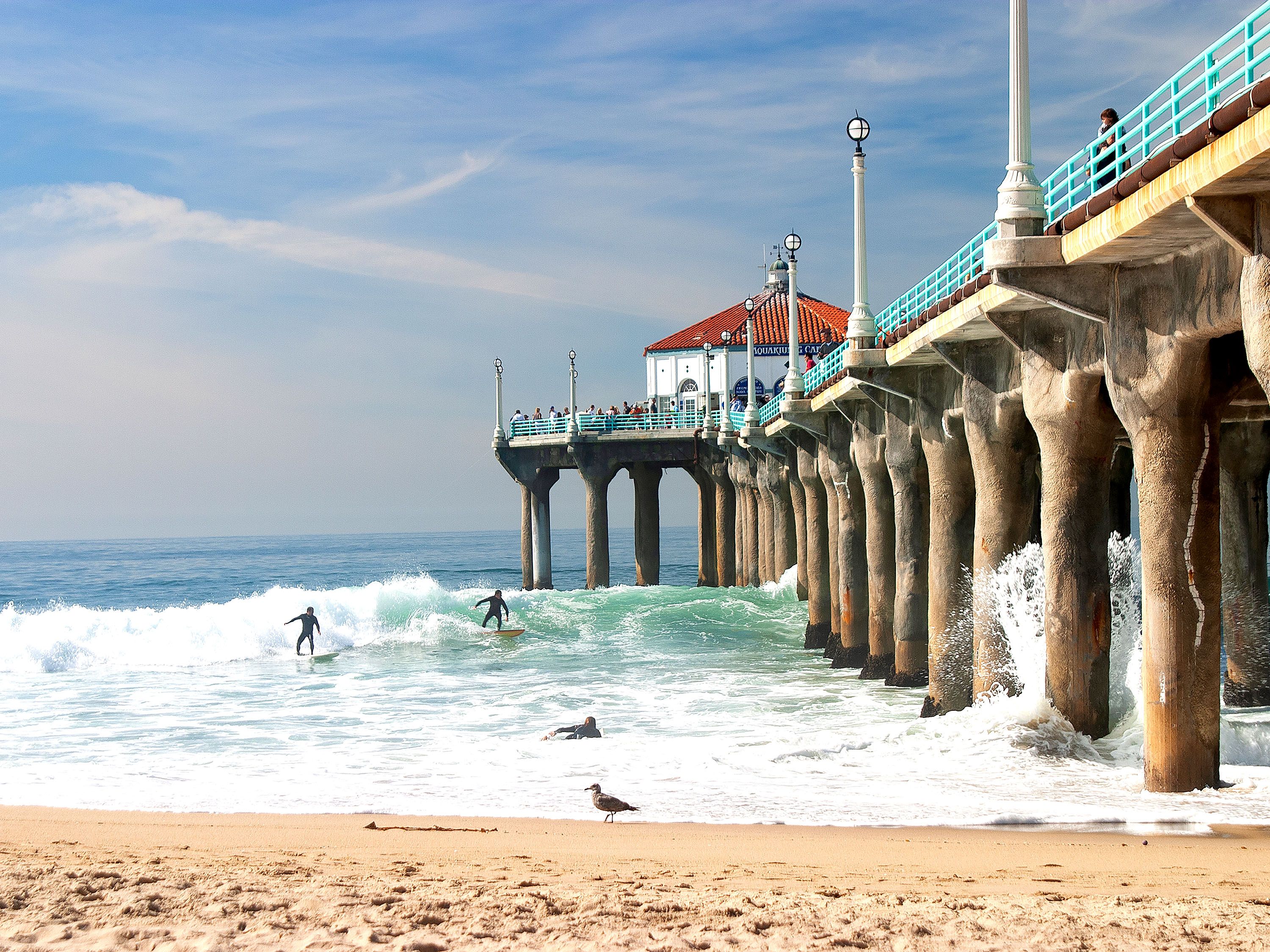 Pier over ocean waves and surfers.