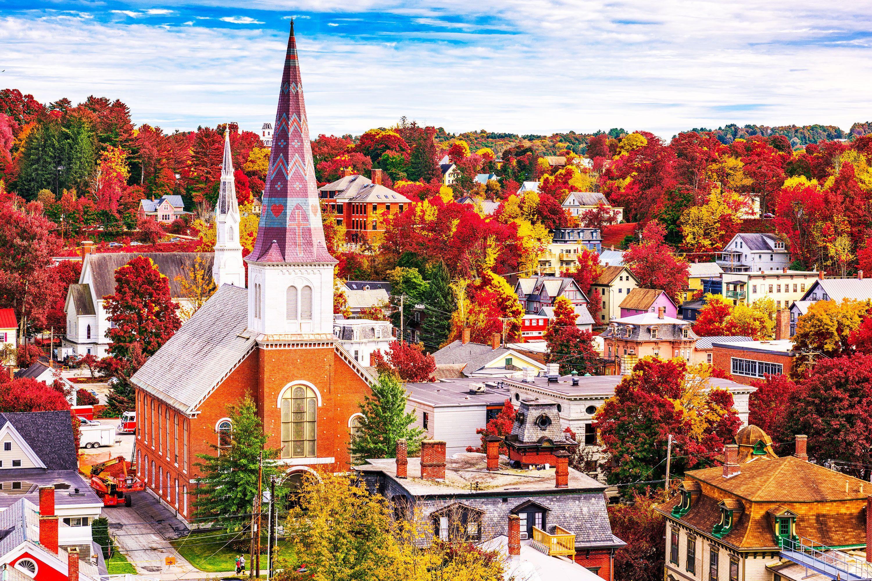 A church with a spire in a town with colorful autumn trees.