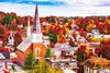 A church with a spire in a town with colorful autumn trees.