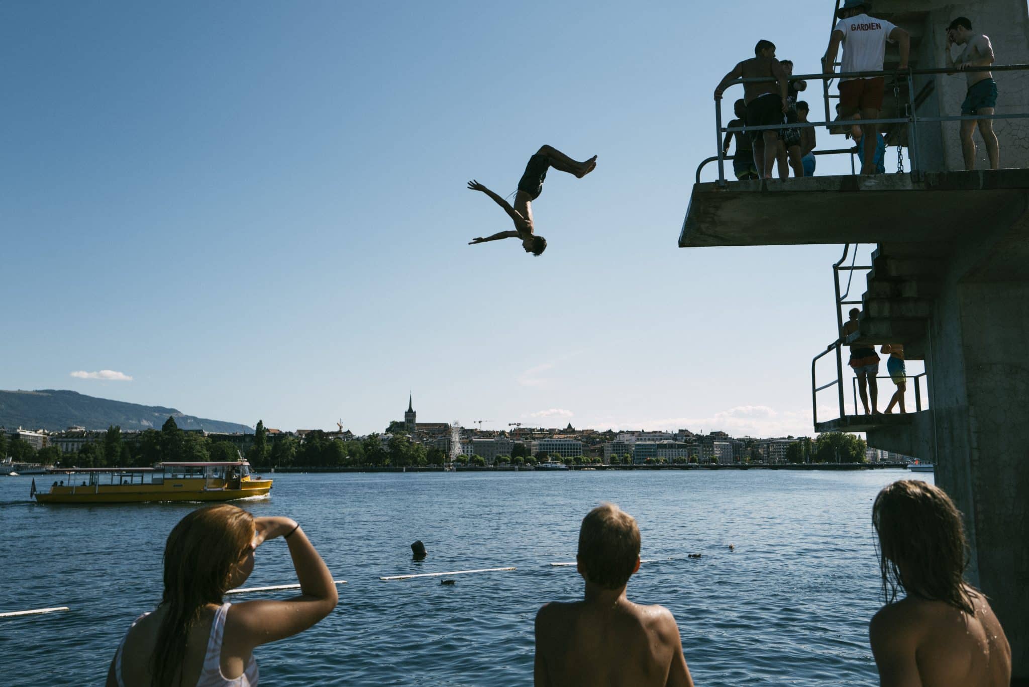 A diver jumps backwards off a platform into Lake Geneva