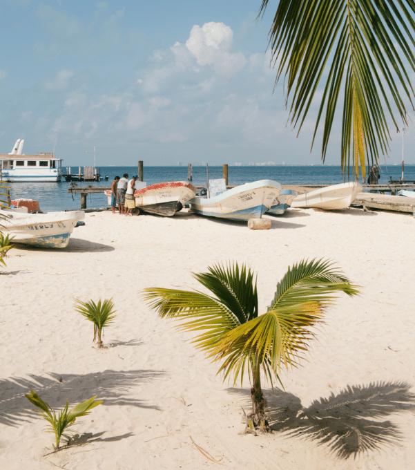 A white sand beach, palm trees, painted fishing boats and azure seas in Cancun, Mexico