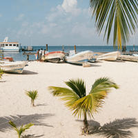 A white sand beach, palm trees, painted fishing boats and azure seas in Cancun, Mexico