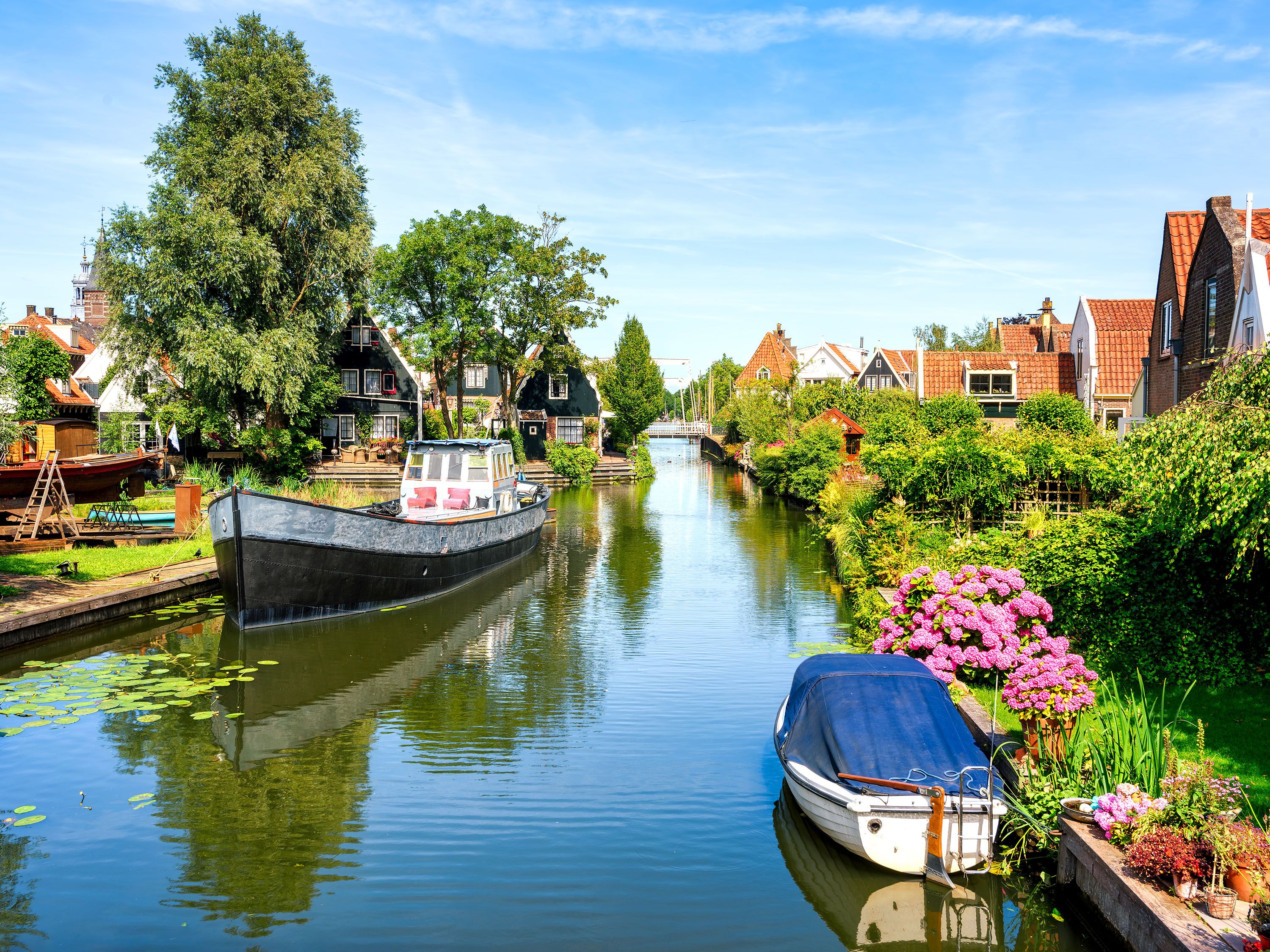 Boats tied up to docks along a canal with homes.