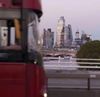 A red London bus crosses one of the bridges across the River Thames