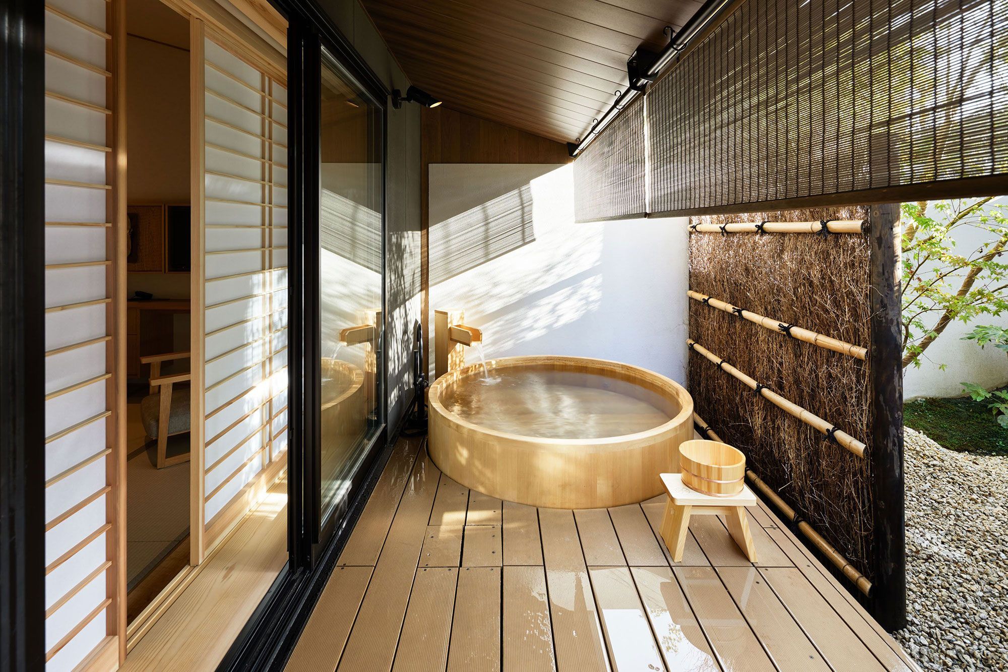A wood hot tub sitting outside on a deck in the sunlight.