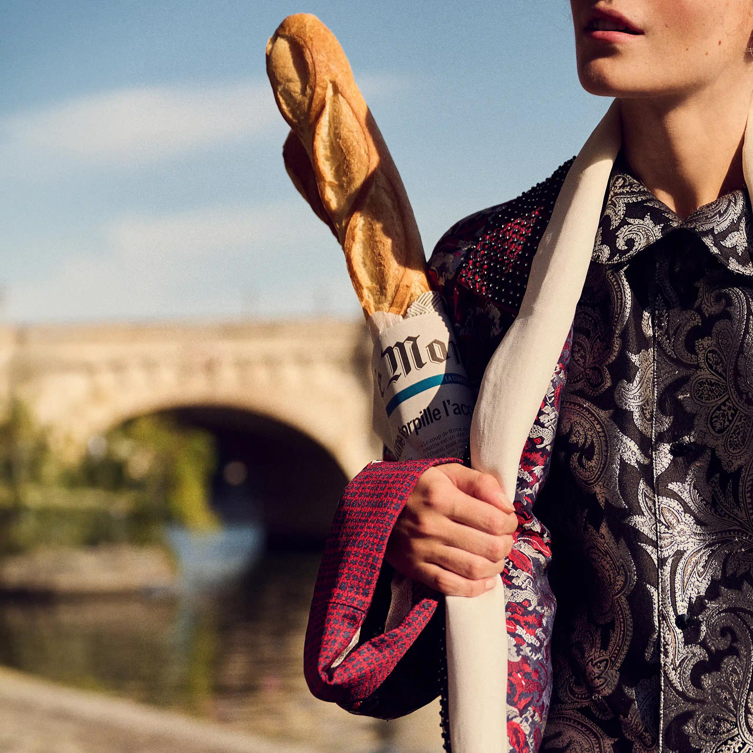 A shopper carrying a fresh baguette tucked into a copy of Le Monde