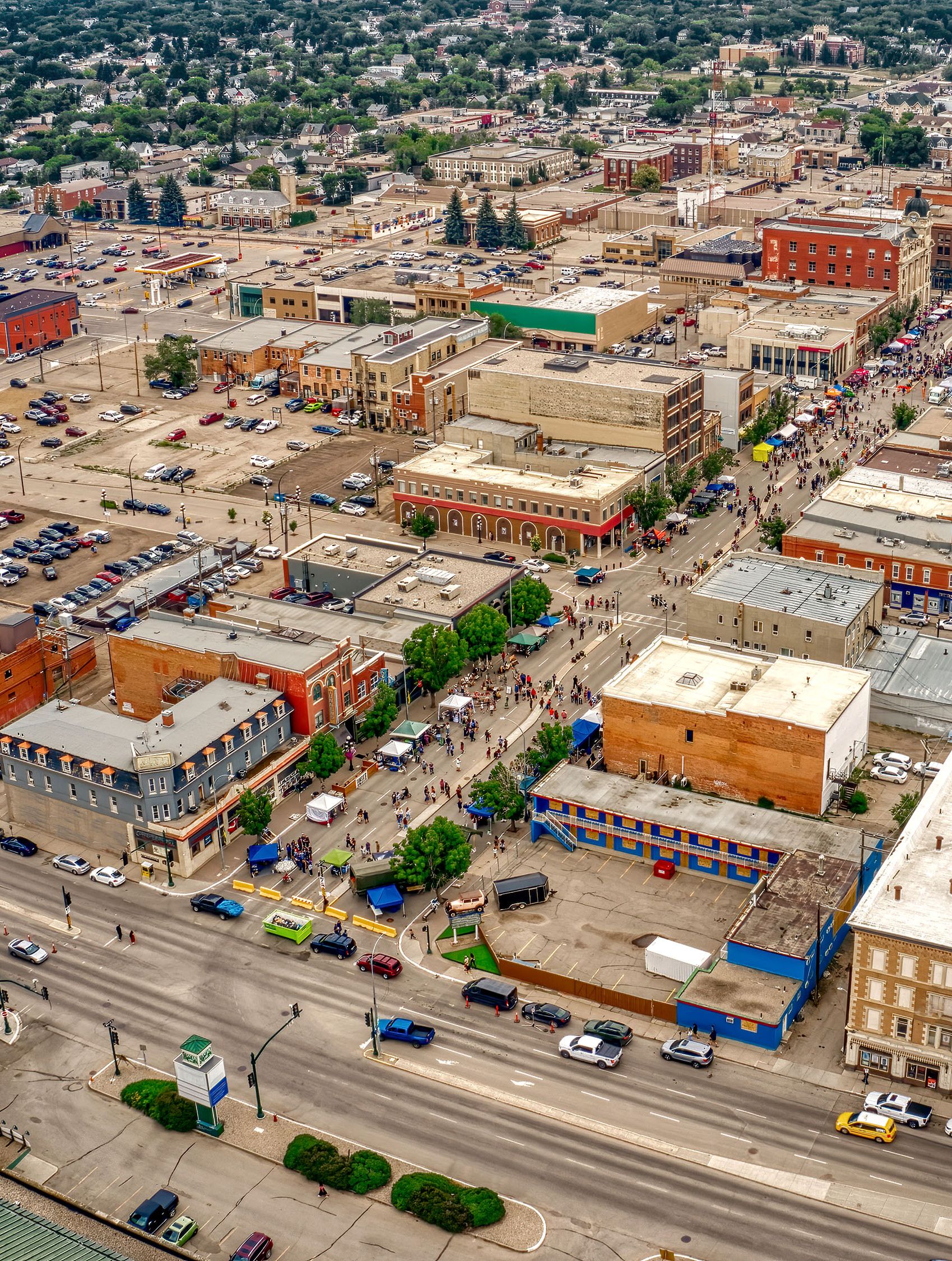 Aerial photo of many four to five story buildings and a street festival.