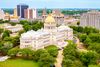 The Mississippi State Capitol building in Jackson, Mississippi featuring a grand white stone capitol with a central dome, columns, and classical architecture set against a clear blue-sky backdrop.