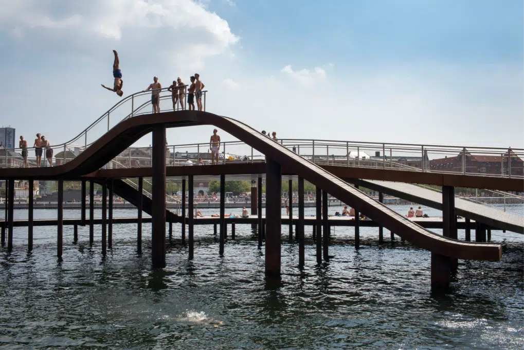 A daring swimmer suspended upside down, mid jump, from a jetty in Copenhagen