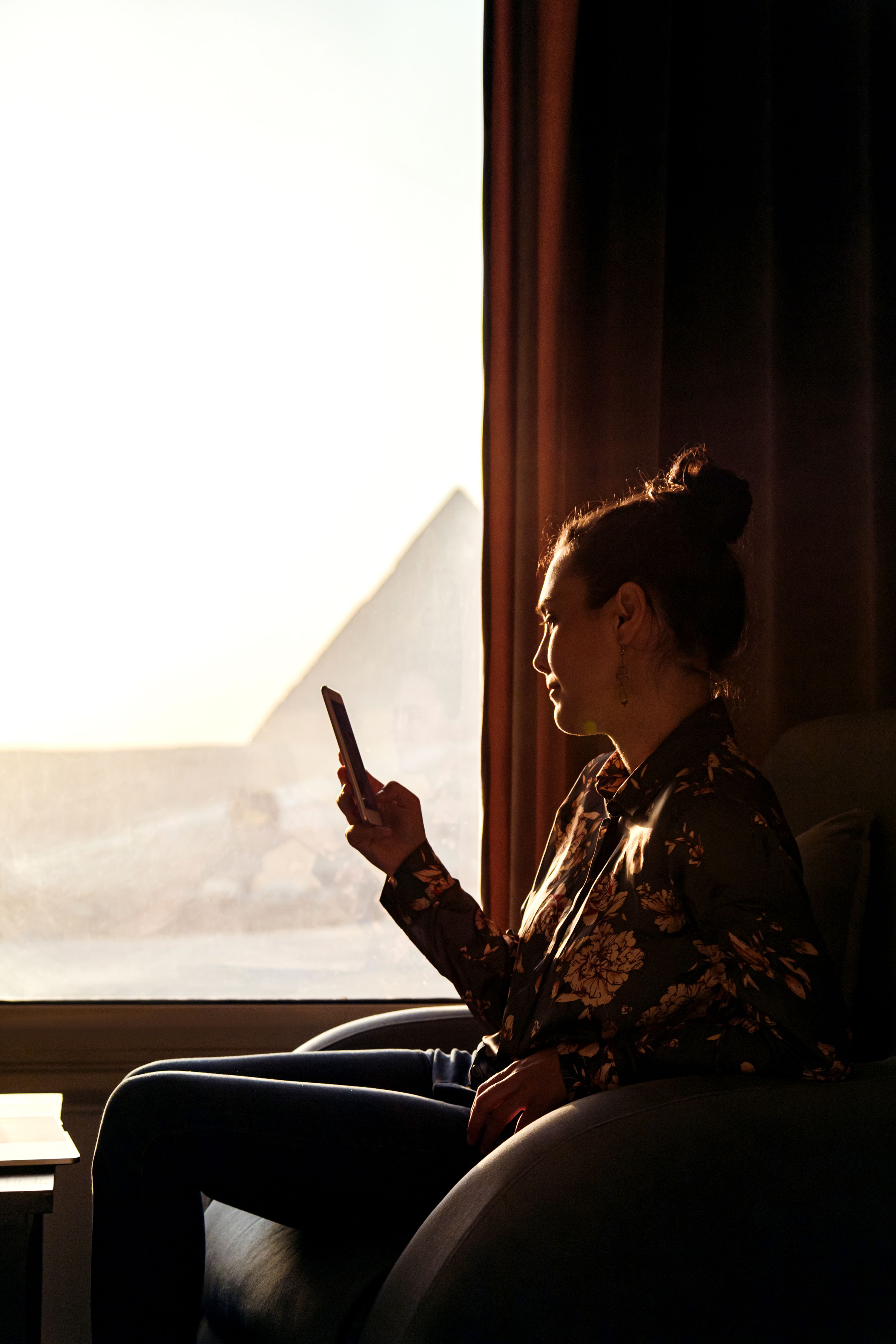 Person sits at a window looking at their phone.