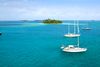 Aerial photo of several sailing boats on blue waters with a small island in the distance.