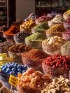 Glass bowls piled high with colorful spices and dried fruit on a Dubai market stall