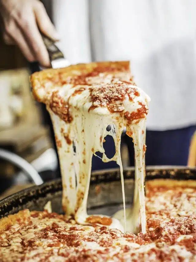 A person picks up a slice of cheesy deep-dish pizza using a metal server