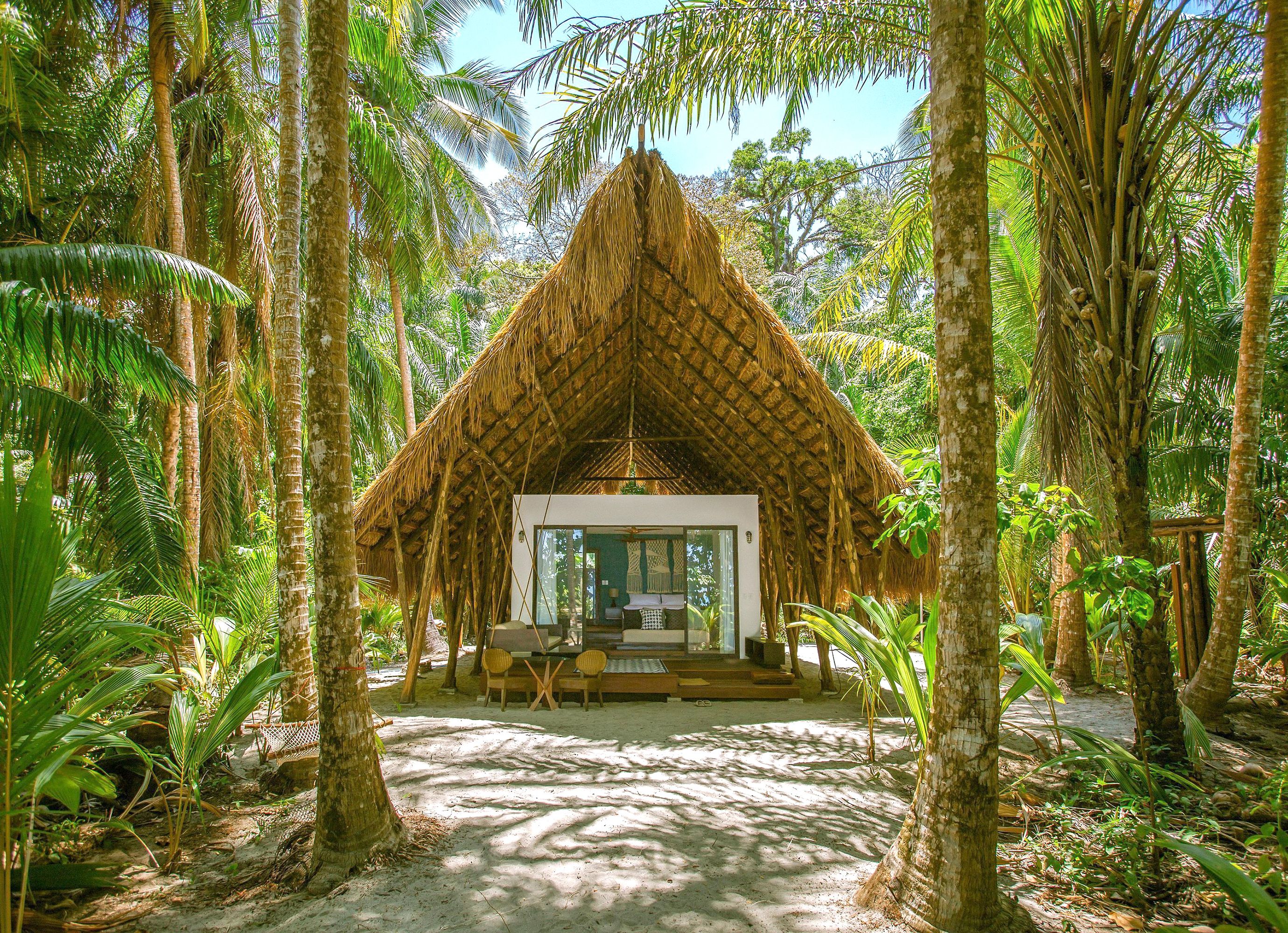 A grass-roof stand-alone cabin with one room inside for sleeping.