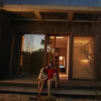 A couple sits on the steps of a home as sun sets