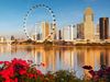 The Singapore skyline and Singapore Flyer reflected in calm waterfront with colorful flowers.