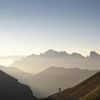 The silhouette of a hiker walks across a landscape of mist-covered mountain ranges