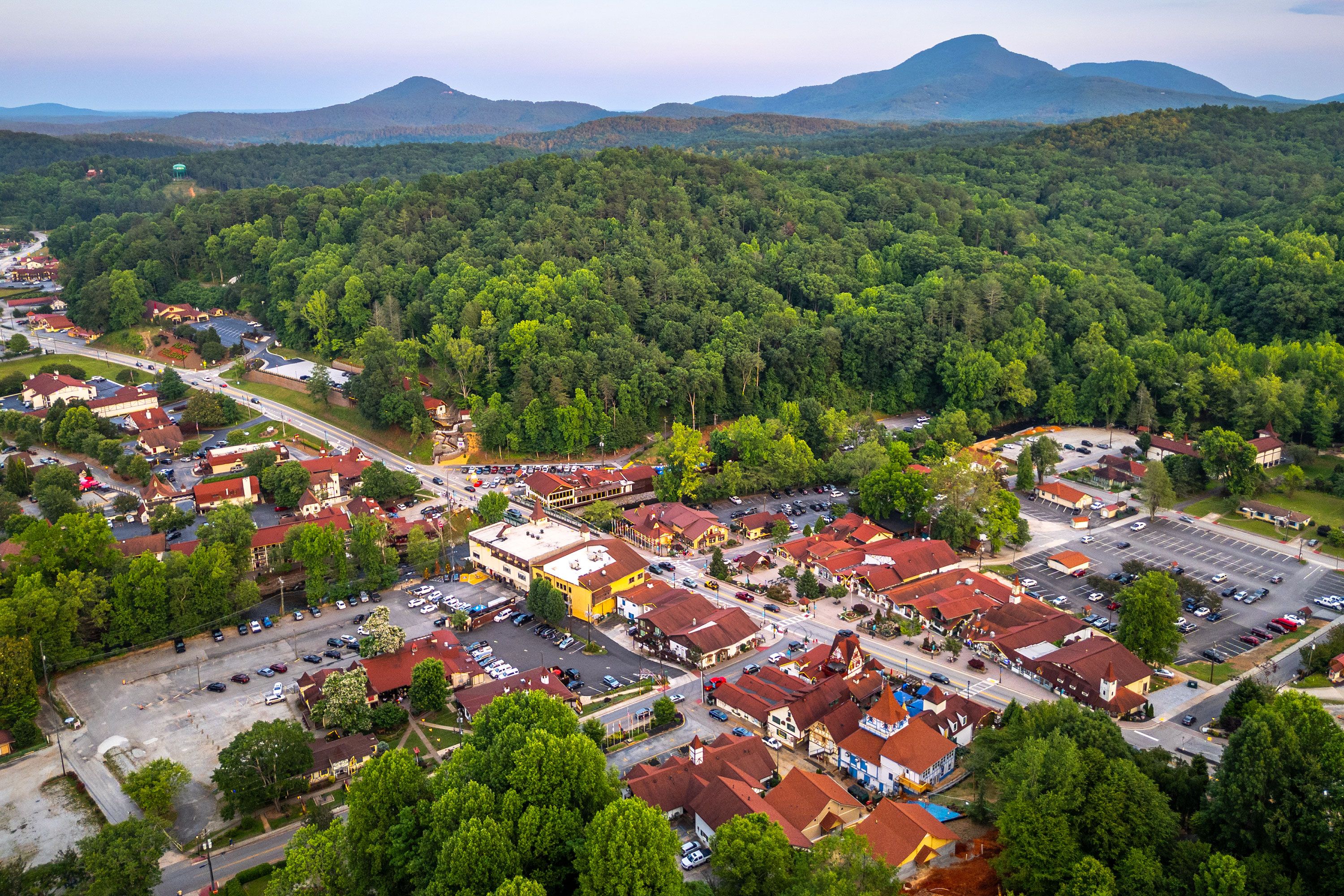 A night view of Helen’s illuminated downtown with Bavarian-style architecture and Mt. Yonah visible behind the town under a dark sky.
