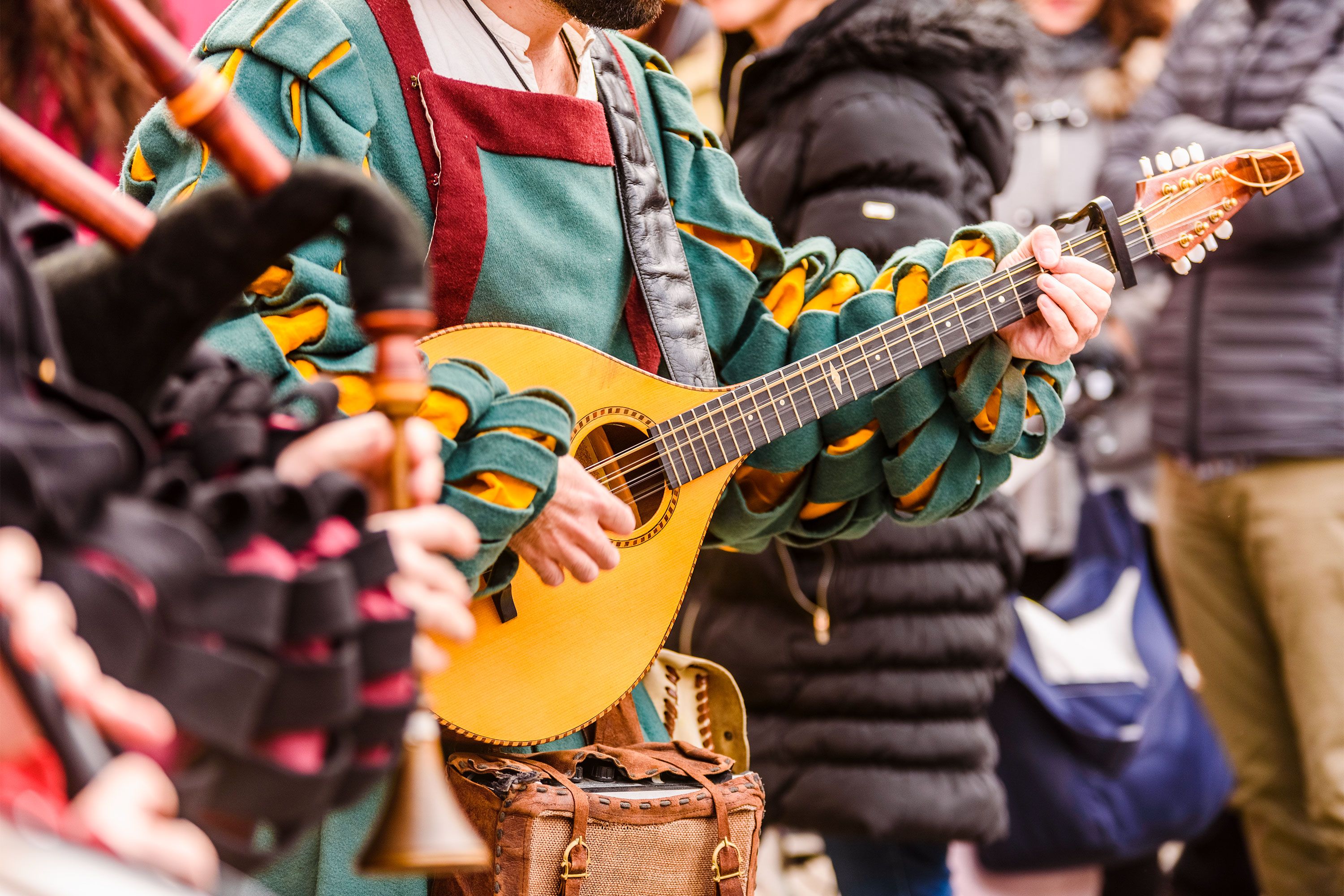 A man dressed in period garb plays a lute-like guitar.