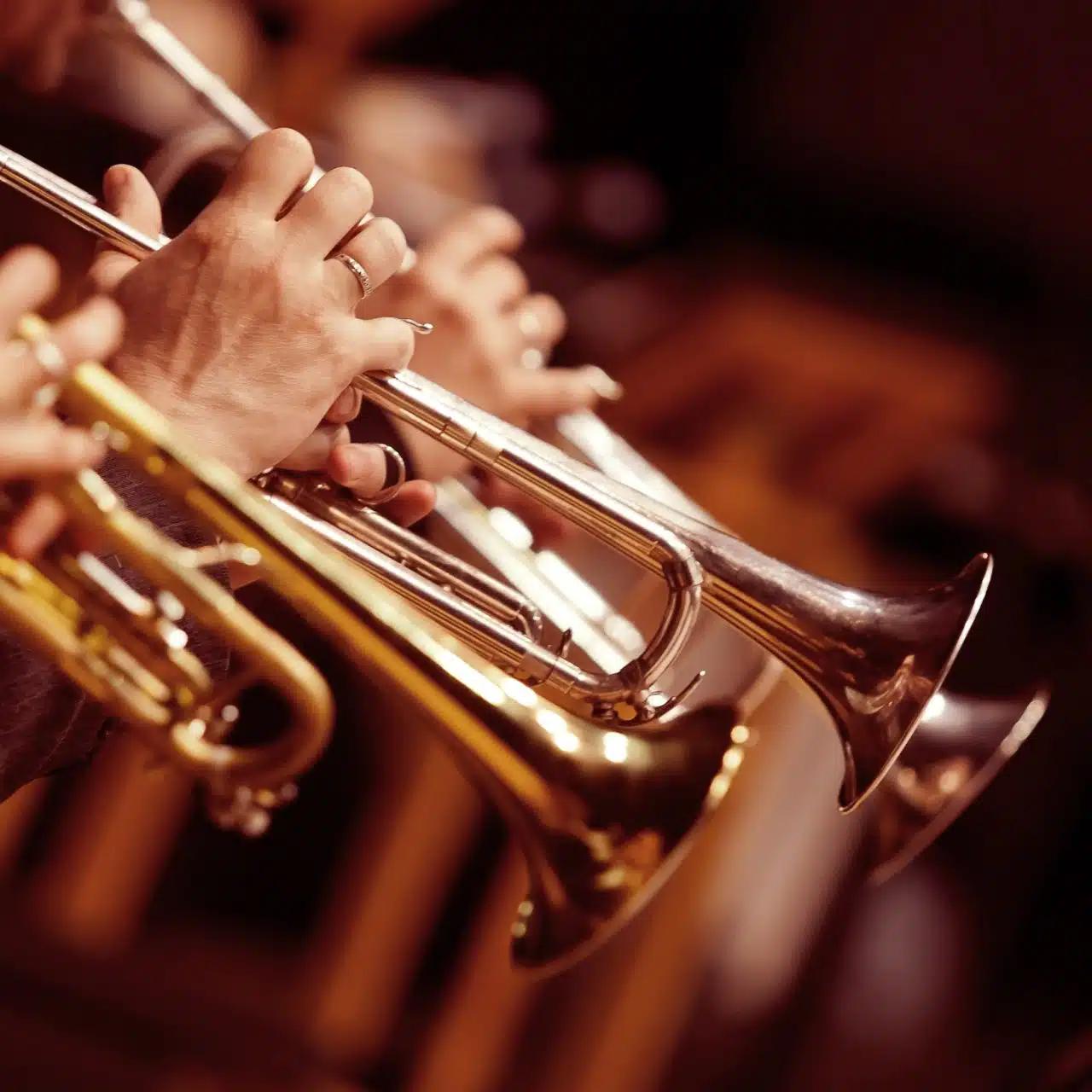 A row of trumpets being held by musicians
