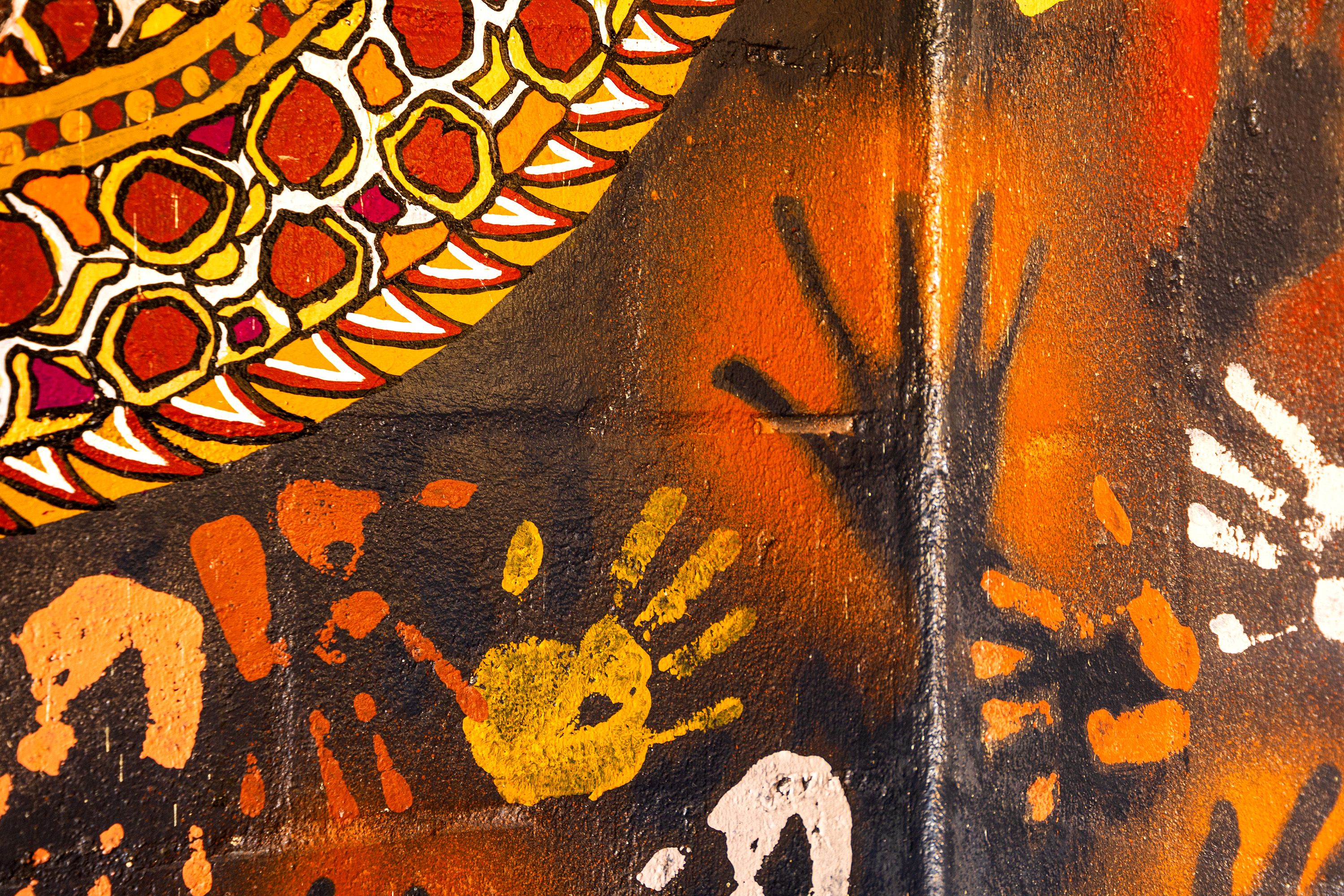 Red and yellow cultural artwork with handprints.