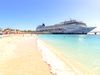 Beach area with sunbathers and cruise ship.