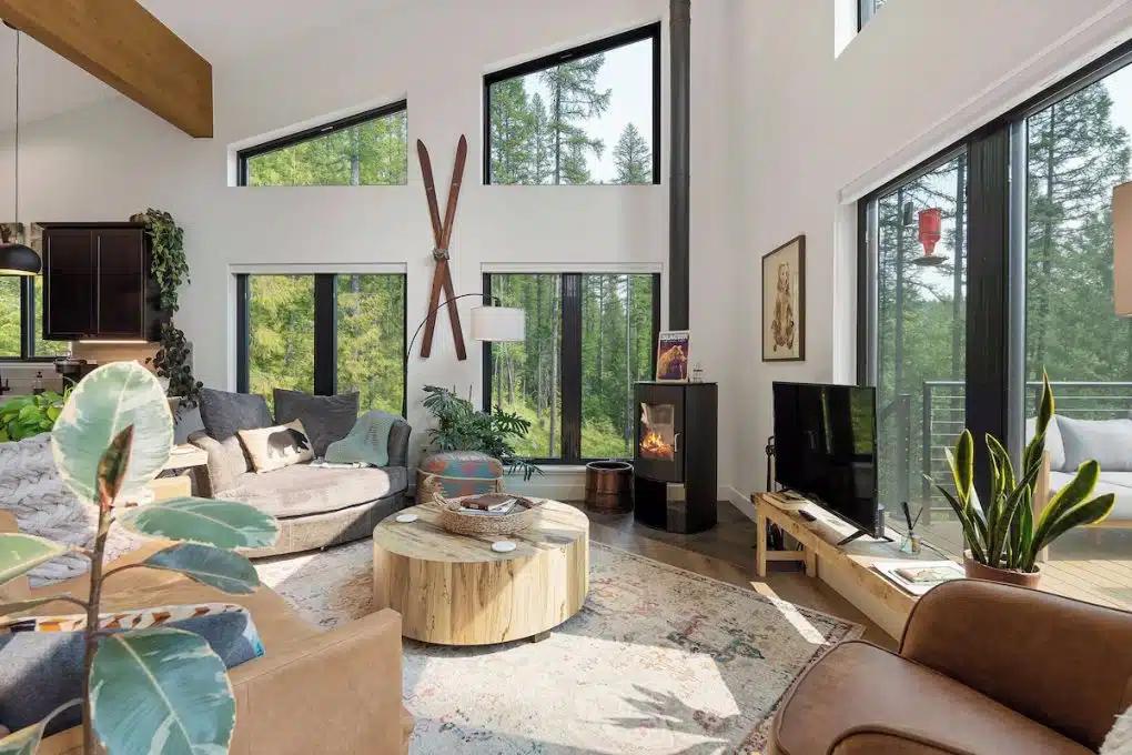 A cozy modern living room of a Montana Vrbo with soft brown furniture, large rug and woodburner