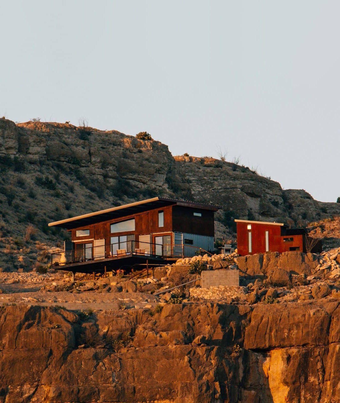 The cliffside Vrbo rental property "The Perch" illuminated by sunlight out in the desert in Terlingua, Texas
