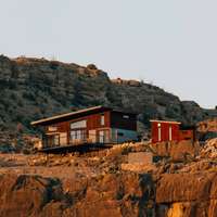 The cliffside Vrbo rental property "The Perch" illuminated by sunlight out in the desert in Terlingua, Texas