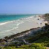Turquoise waters meet white sands leading to rocky cliffsides along the coast in Tulum, Mexico