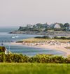 A sandy bay with clapboard homes beyond in Cape Cod