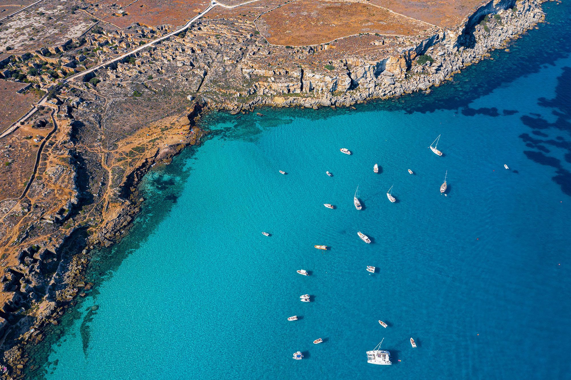 Aerial view of the cliffs, sea and boats at Cala Rossa, Favignana, Italy.