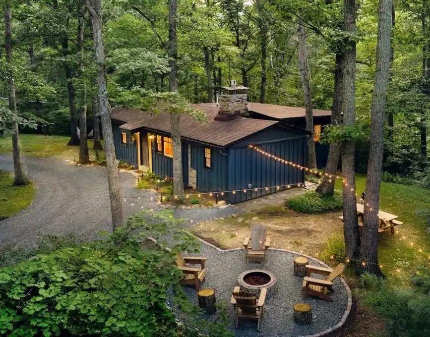 A blue-painted cabin Vrbo in the Shenandoah Valley woods with festoon lights strung between trees