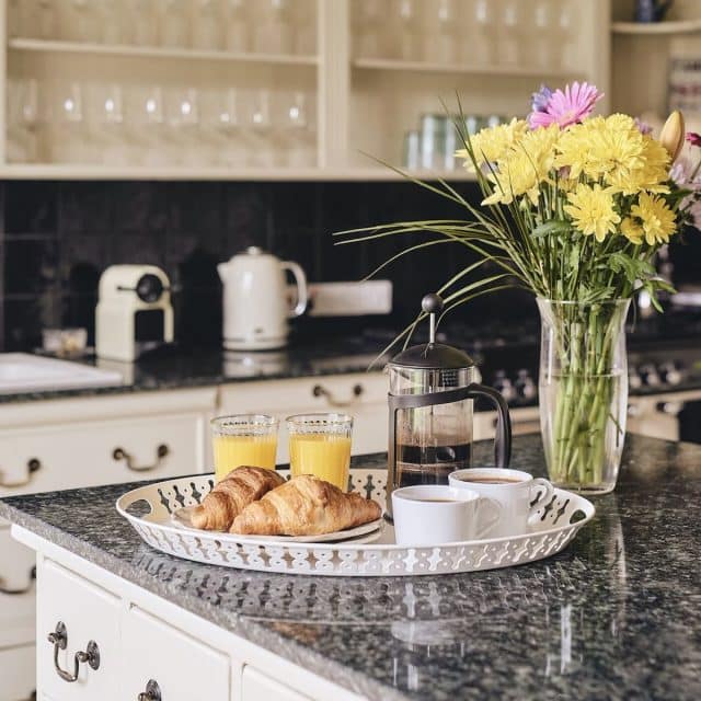A tray on a counter is loaded with croissants, orange juice, and coffee, part of a hearty breakfast, as prepared in the Vrbo's well-equipped kitchen