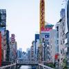 The Dōtonbori canal is lined by tall, colorful buildings on a clear day in Osaka, Japan