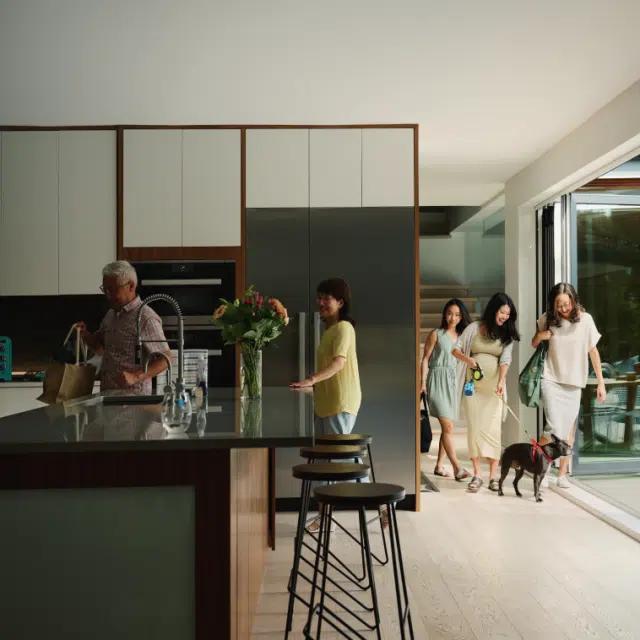 A multi-generational family bringing groceries home to to a modern vacation rental kitchen