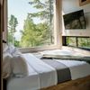The bedroom of a forest cabin in Split Rock Lighthouse State Park, with a large picture window by the bed giving forest views