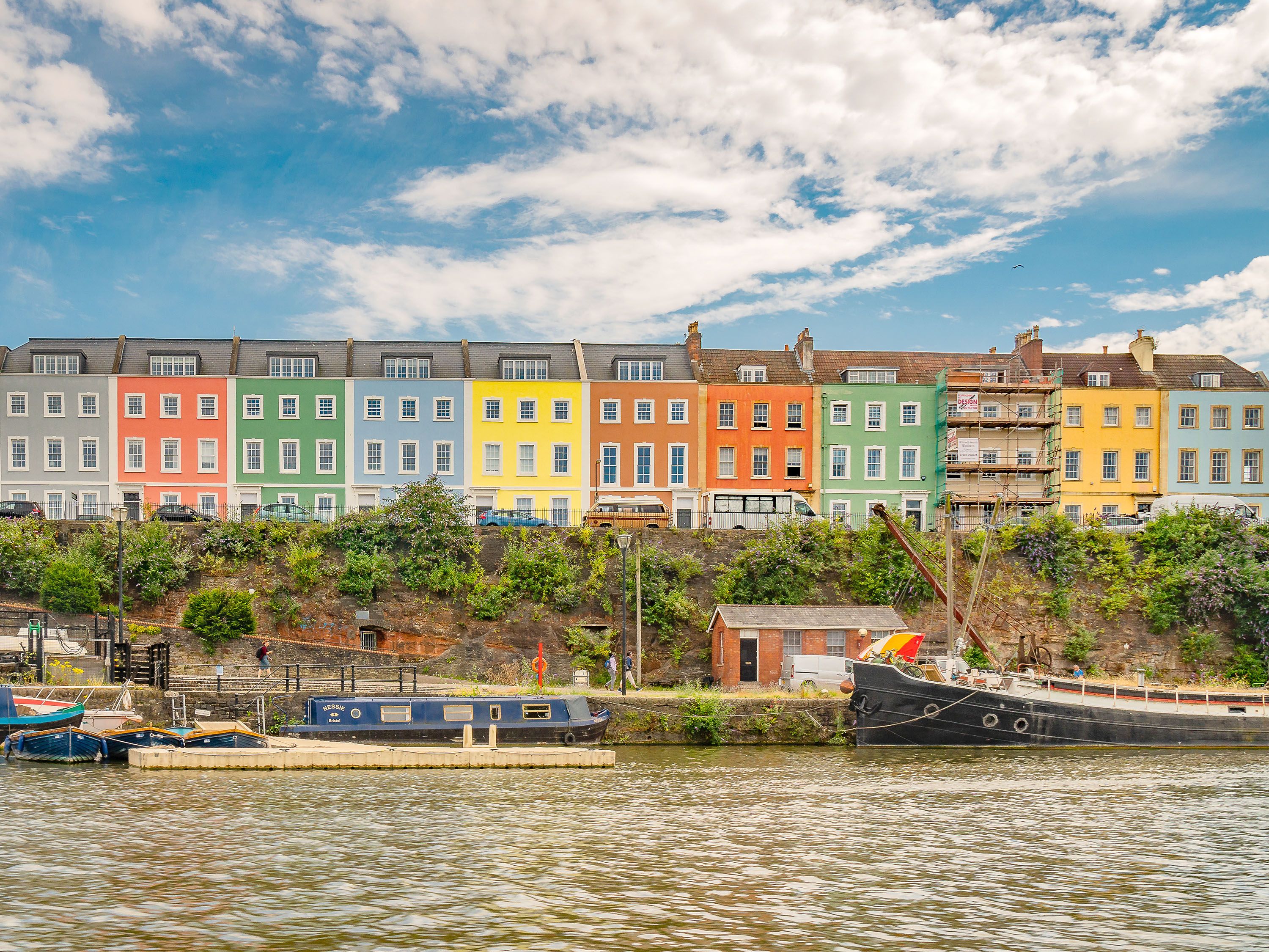 Colorful row homes along the river with boats tied to shore.