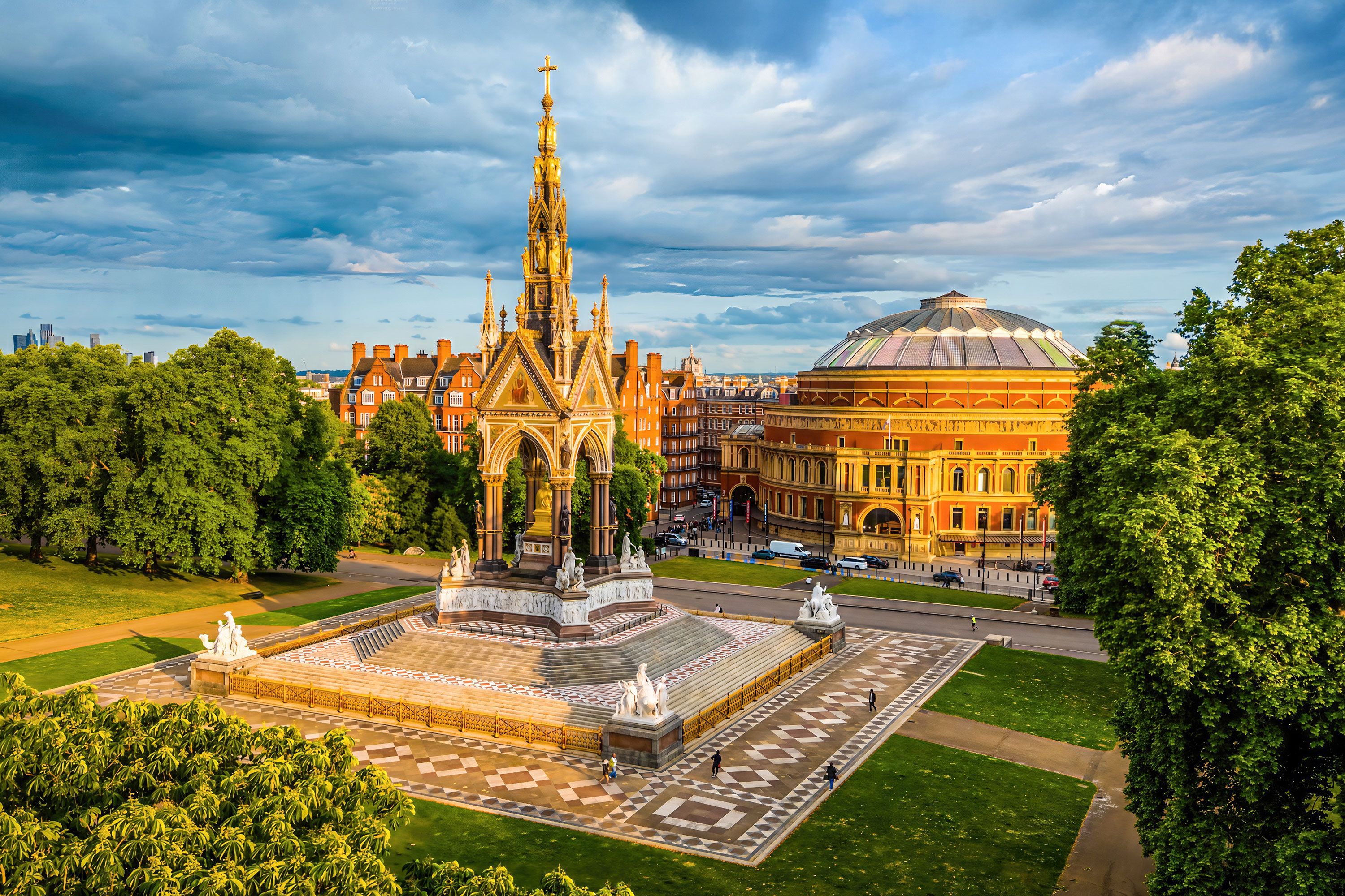 Aerial view of memorial structure in park  with city skyline in the background under cloudy sky.