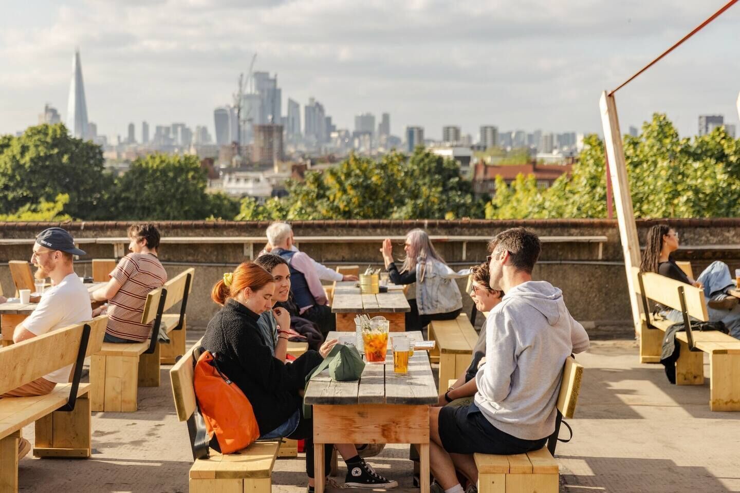 Groups of people have drinks on a sunny day at the rooftop bar Frank's Café in Peckham, London, England