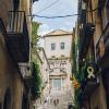 People walk up a set of stone stairs between residential buildings with balconies in Girona, Spain