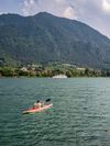 A person kayaks across Lake Iseo in Brescia, Italy, with mountains in the distance