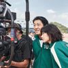 Two stars of Squid Game look at a camera in a behind the scenes moment