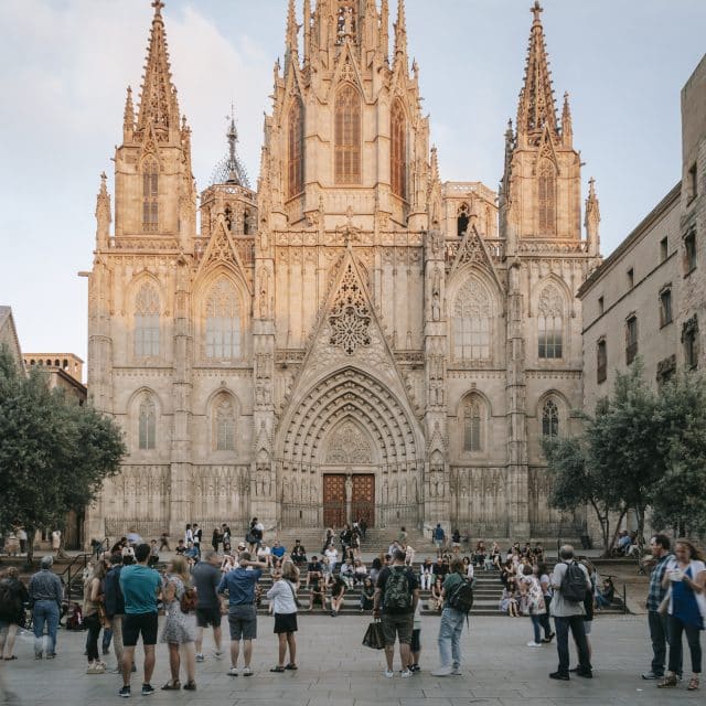 People mill about in the square in front of the Barcelona Cathedral in Spain