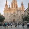 People mill about in the square in front of the Barcelona Cathedral in Spain