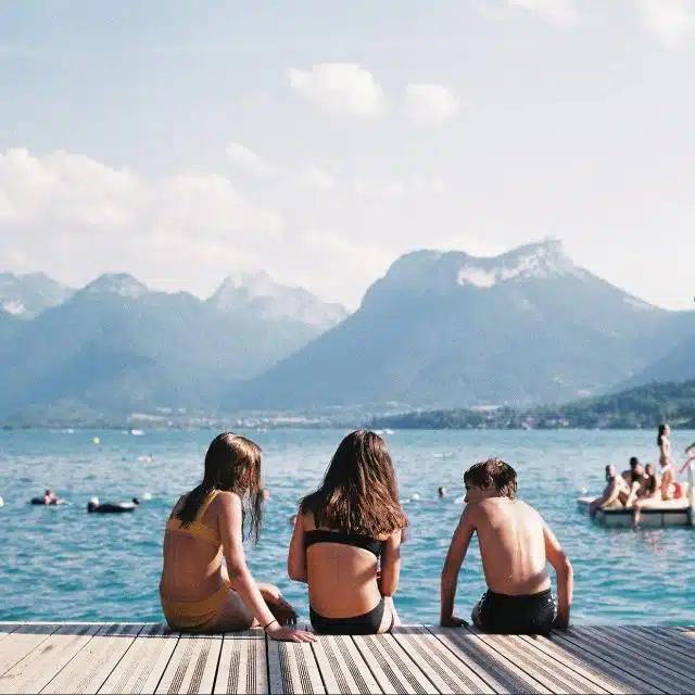 Swimmers take a break from a dip in the waters of Lake Annecy, with mountains behind