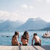 Swimmers take a break from a dip in the waters of Lake Annecy, with mountains behind